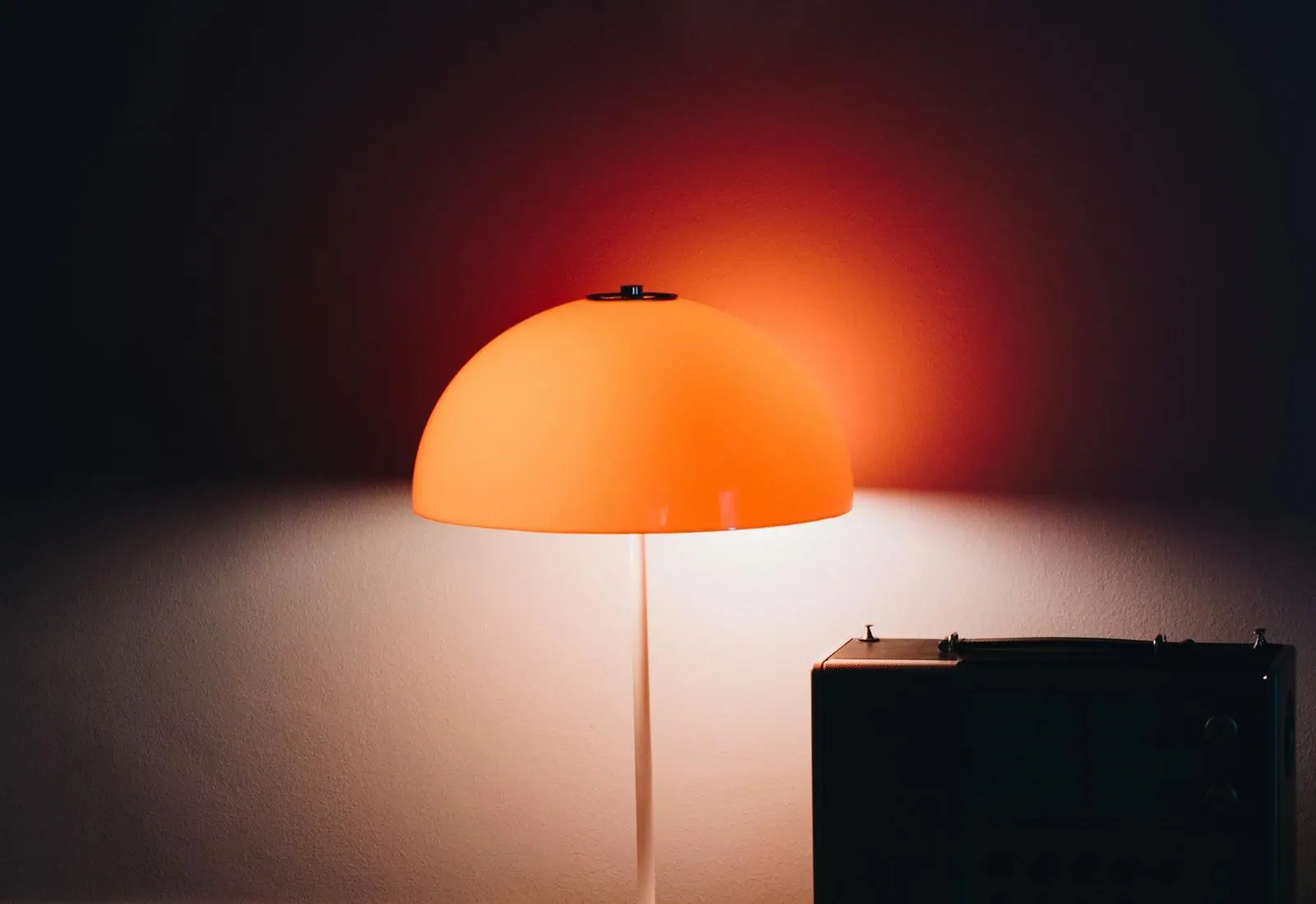 A lit lamp on a desk in a dark room