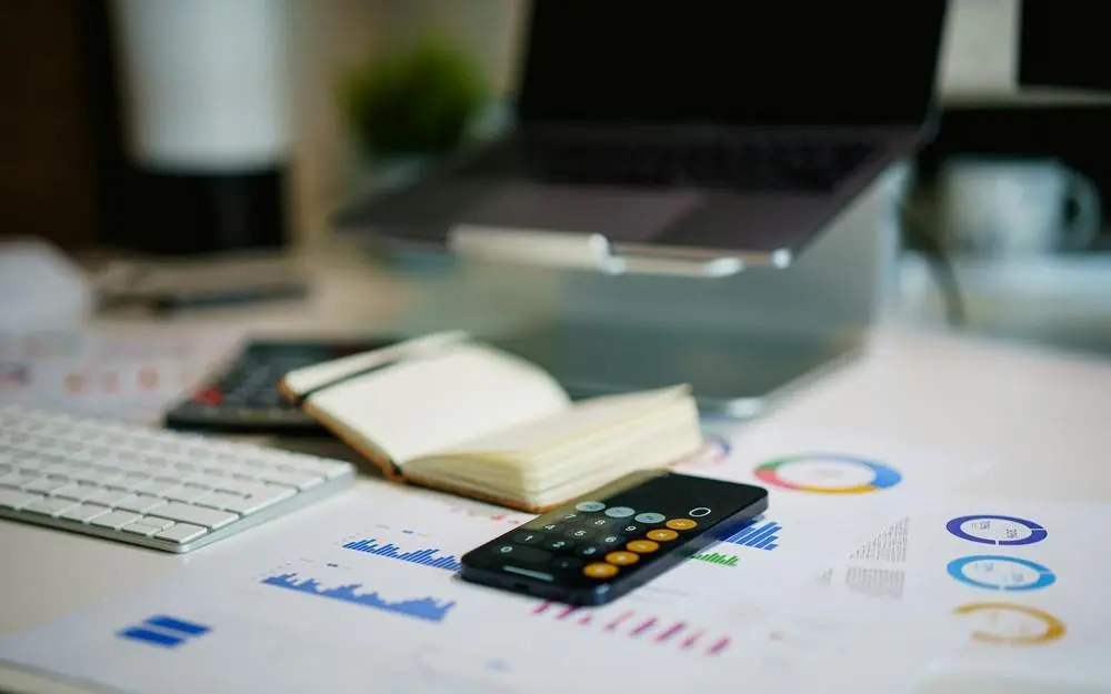 A desk with financial statements, a phone and a notebook