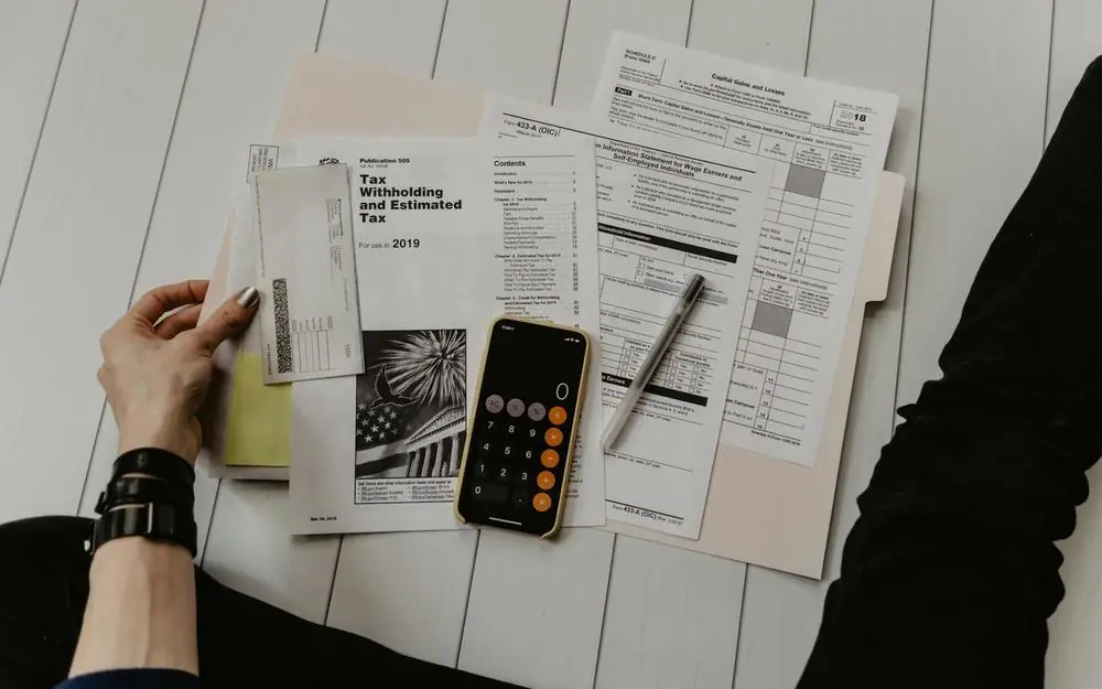 Hands sorting financial papers beside a calculator and pen