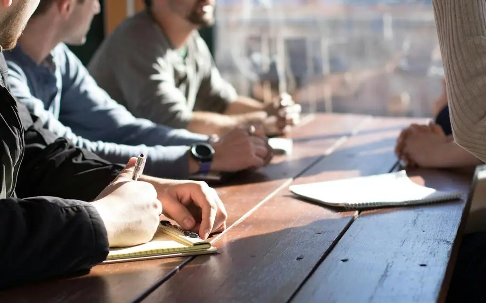 People discussing papers around a wooden table