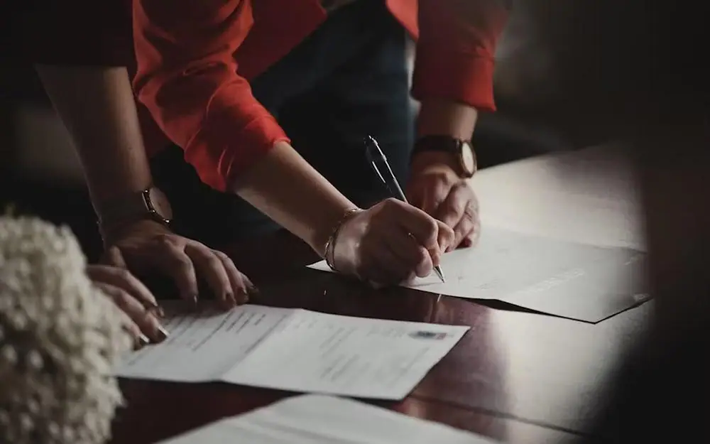 Two people signing documents at a table